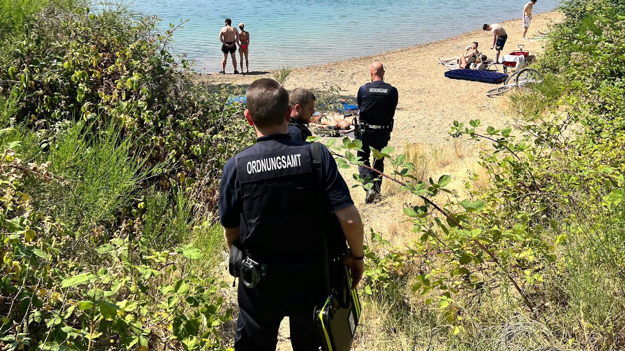Männer vom Leverkusener Ordnungsamt auf dem Weg zum verbotenen Strand am Stöckenbergsee