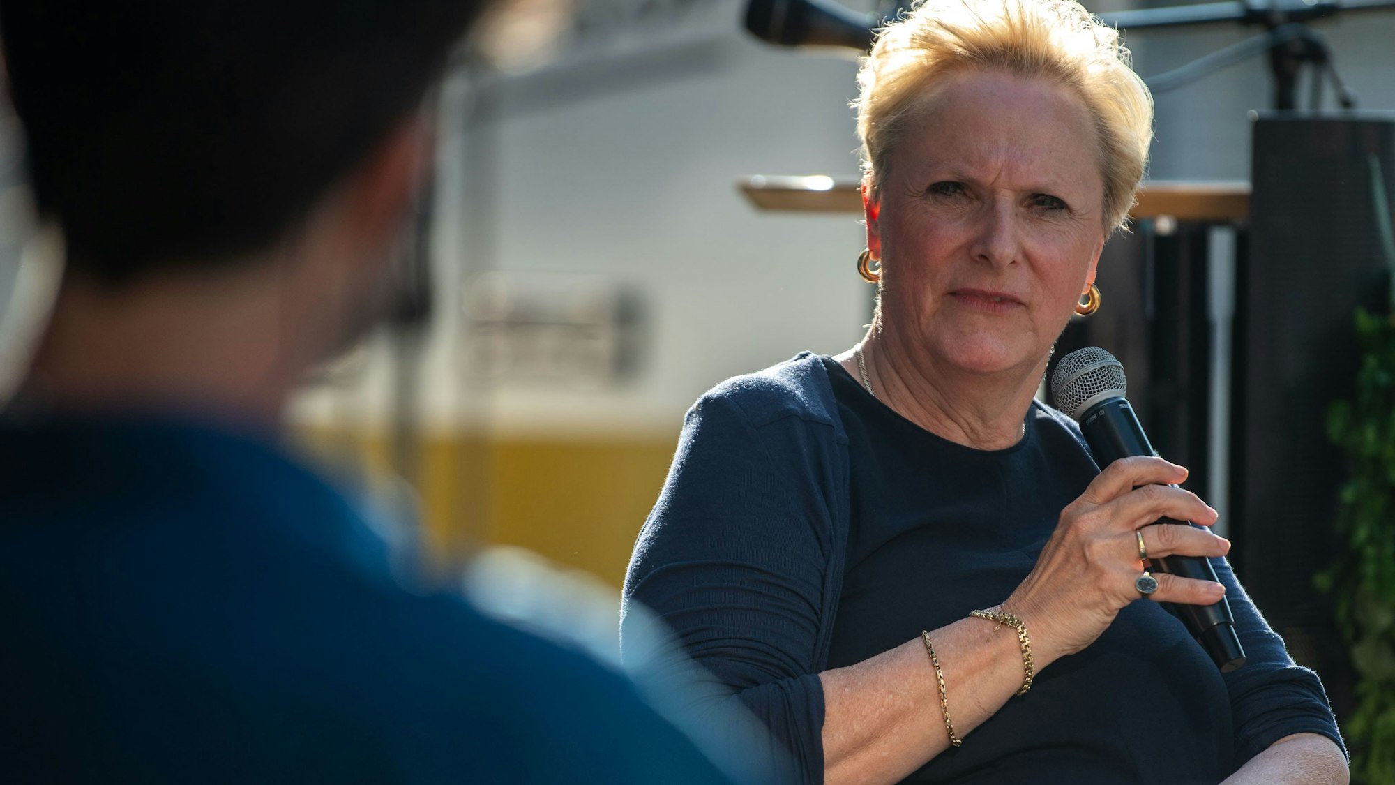 Ein Mann und eine Frau mit einem Mikrofon in der Hand reden auf einer Podiumsveranstaltung miteinander.