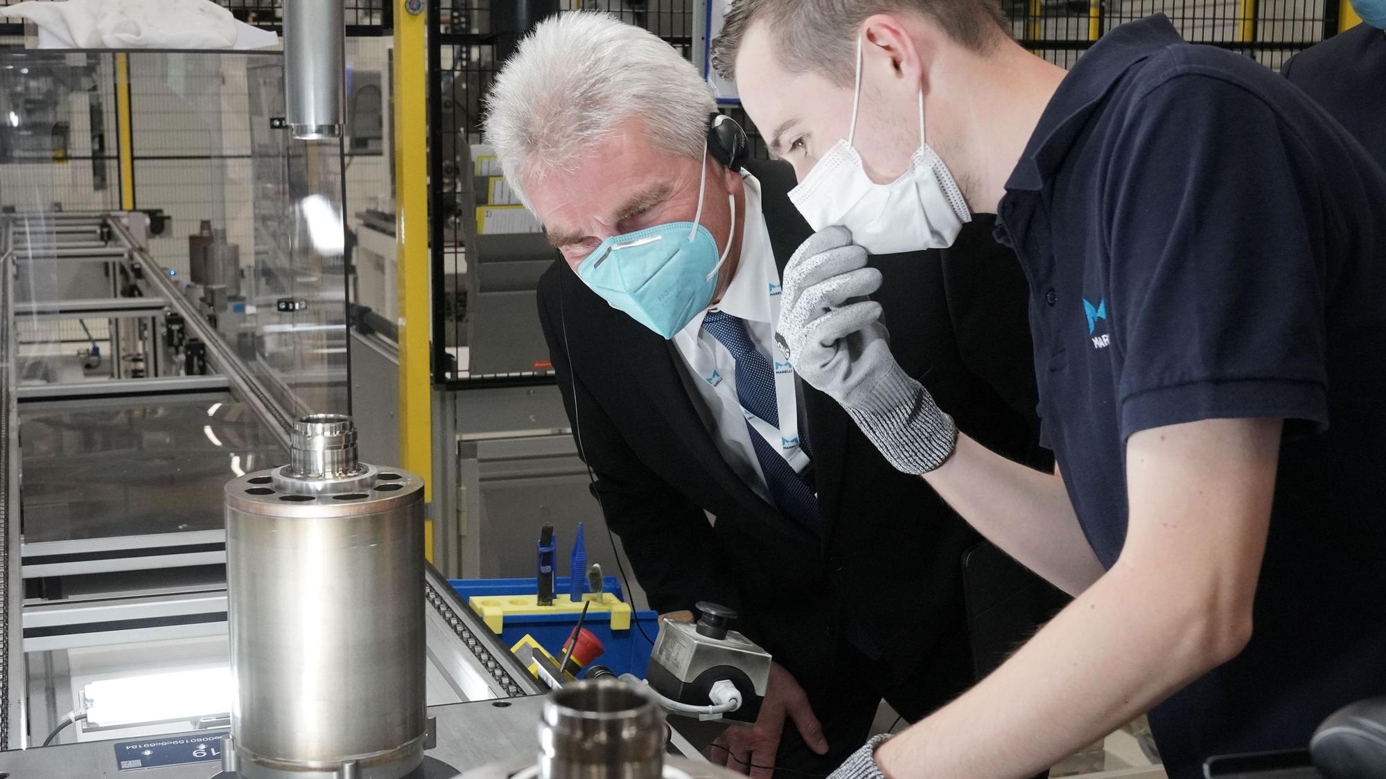Köln, 12.10.2021 – Besuch des NRW Wirtschaftsministers Andreas Pinkwart im Marelli Elektromotorenwerk in Köln. Marelli-Mitarbeiter Sven Virnich erklärt dem Wirtschaftsminister Andreas Pinkwart die Sichtkontrolle des fertigen Elektromotoren-Rotors. Rechts: Werksleiter Stephan Ulner. --- Foto Copyright: Marelli/Friedrich Stark --- Verwendung honorarfrei