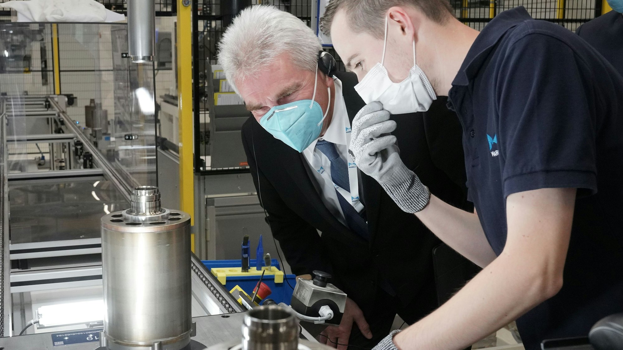 Köln, 12.10.2021 – Besuch des NRW Wirtschaftsministers Andreas Pinkwart im Marelli Elektromotorenwerk in Köln. Marelli-Mitarbeiter Sven Virnich erklärt dem Wirtschaftsminister Andreas Pinkwart die Sichtkontrolle des fertigen Elektromotoren-Rotors. Rechts: Werksleiter Stephan Ulner. --- Foto Copyright: Marelli/Friedrich Stark --- Verwendung honorarfrei