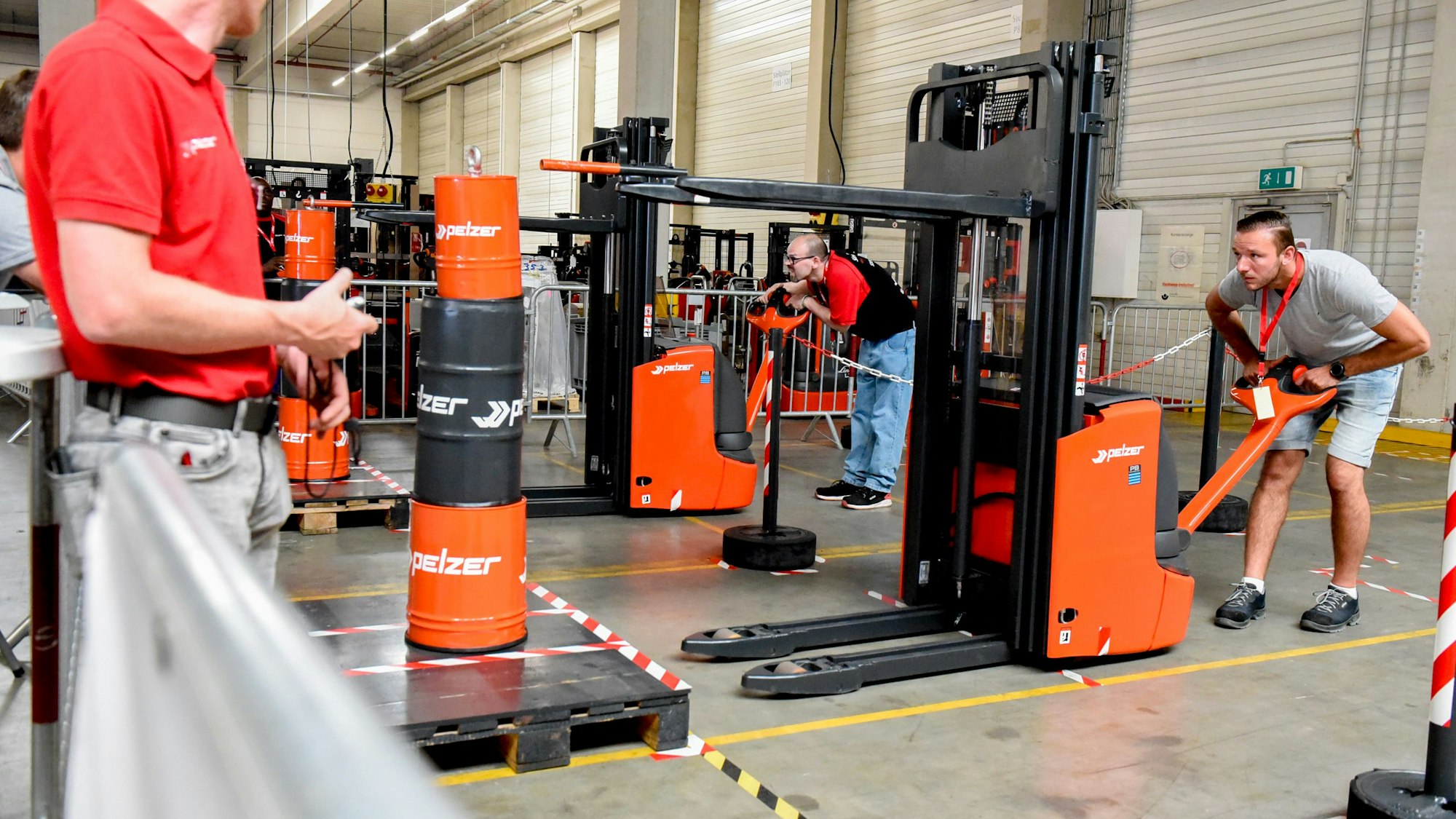 Ein Mann stapelt farbige Tonnen mithilfe eines Gabelstaplers.