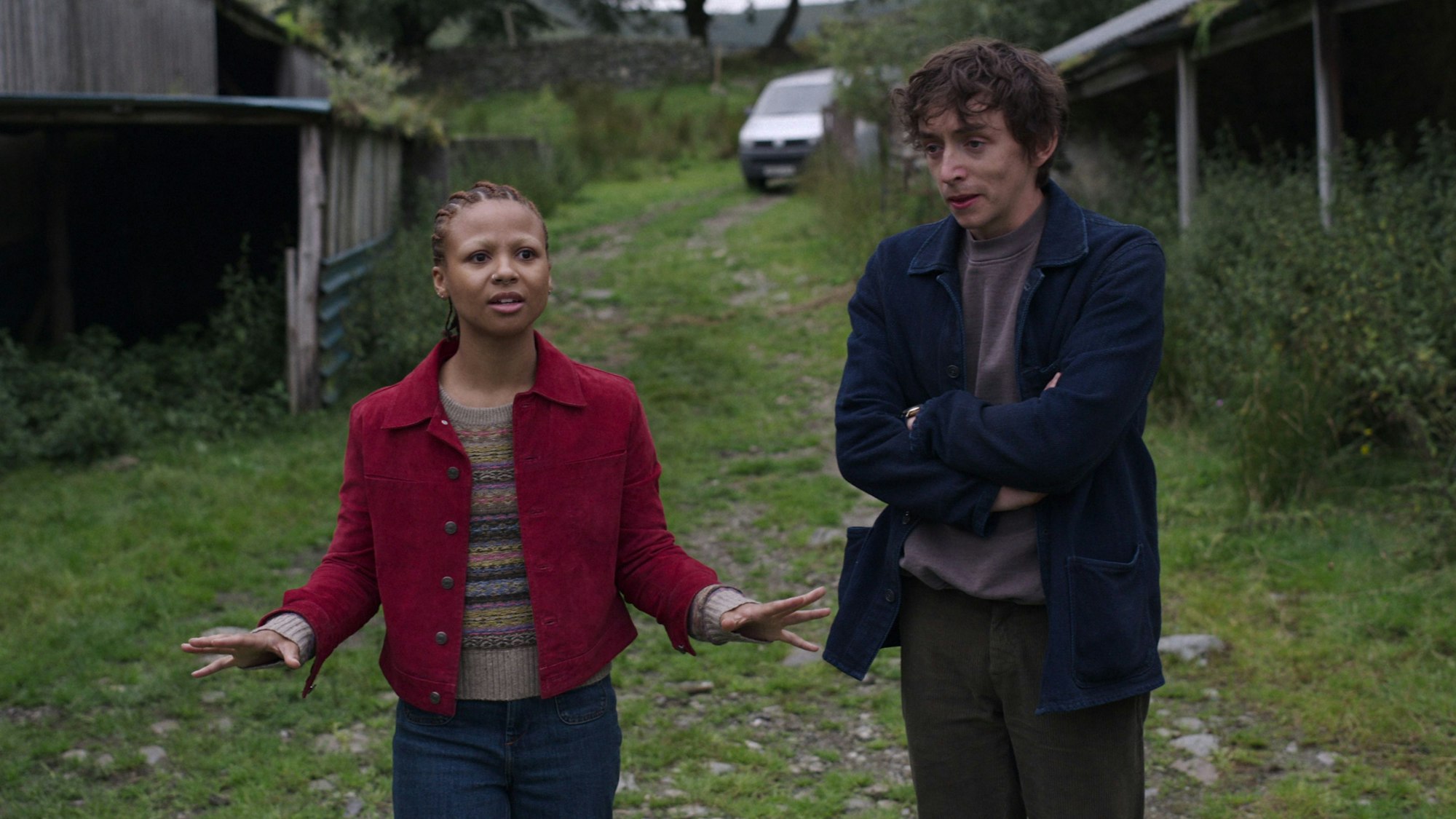 Zwei junge Menschen stehen auf einer Wiese in einem Hinterhof