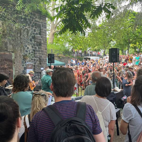Viele Menschen stehen um eine Band in einem Park.