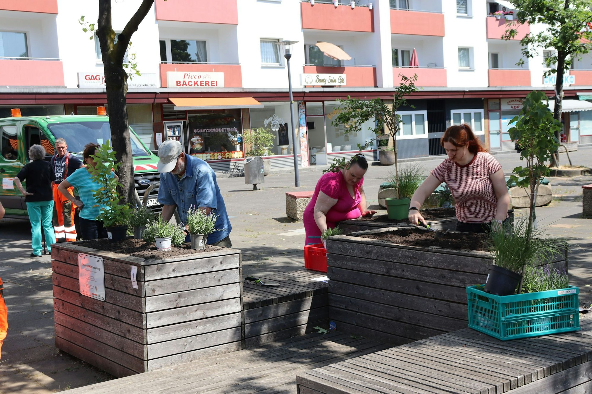 Menschen stehen an Hochbeeten und bepflanzen diese.