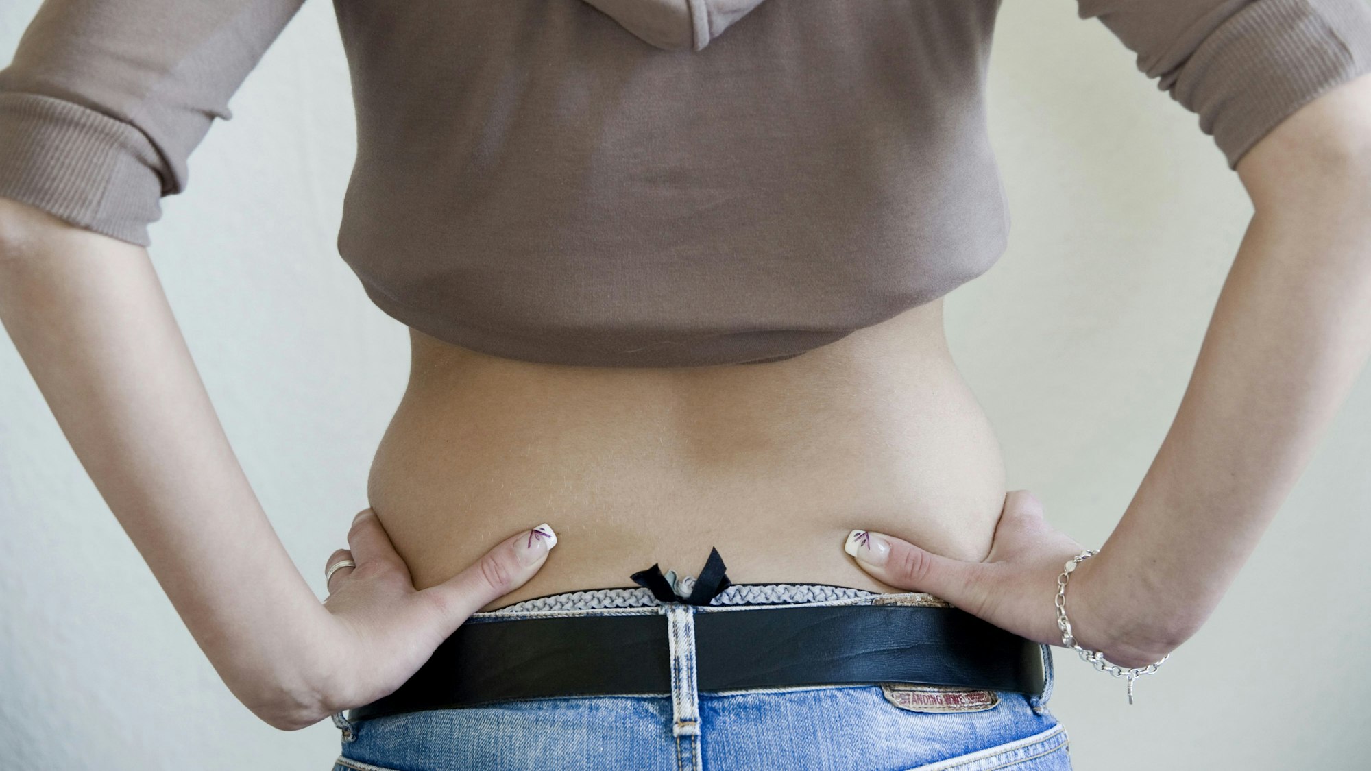 Eine junge Frau, von hinten fotografiert, mit bauchfreiem Oberteil.
