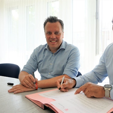 Bürgermeister Sacha Reichelt und Frank Pischke von der Telekom sitzen an einem Tisch im Euskirchener Rathaus und unterzeichnen Verträge zu Glasfaser-Ausbau in der Euskirchener Innenstadt.