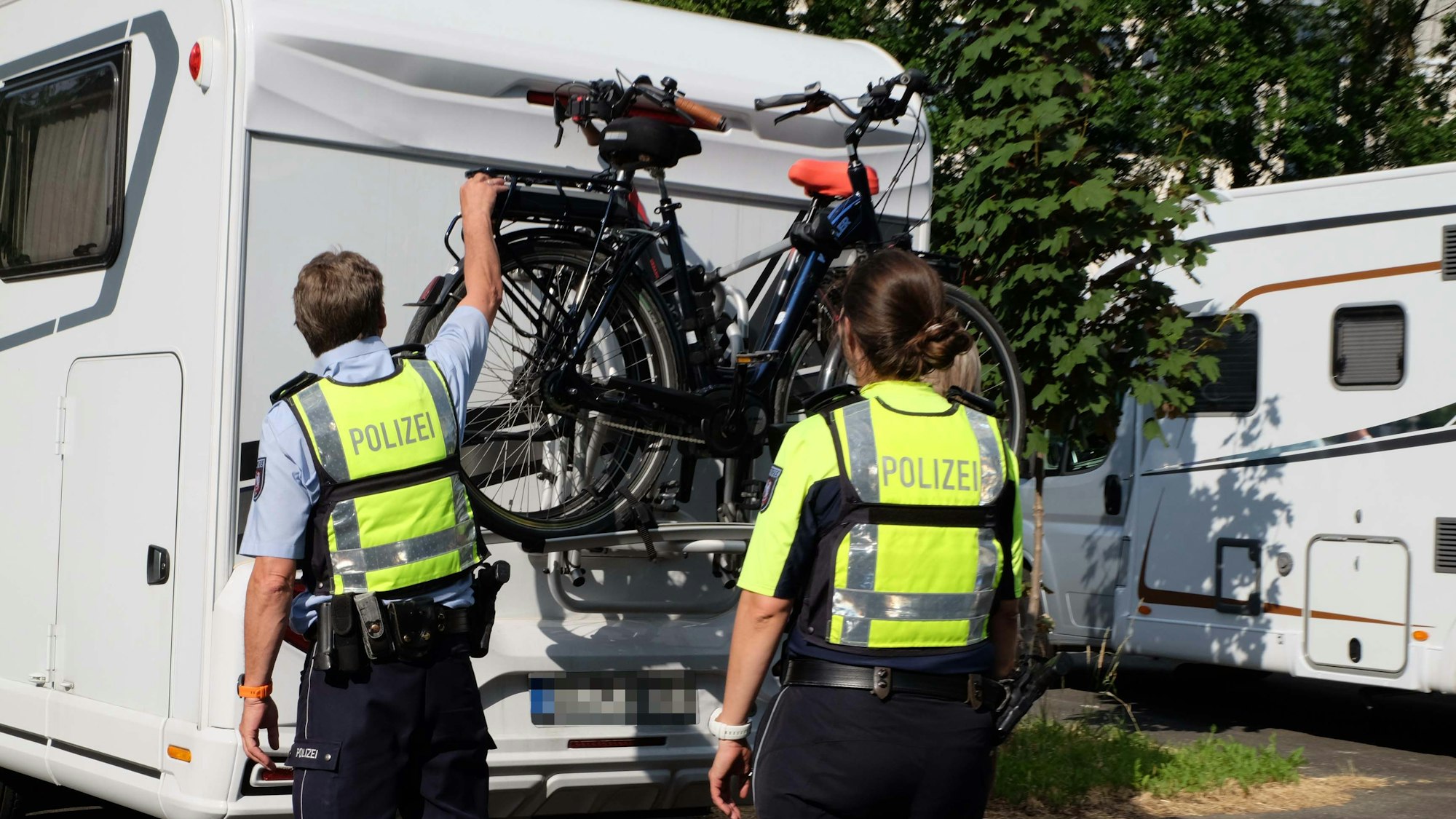 Zwei Polizisten überprüfen einen Wohnwagen.