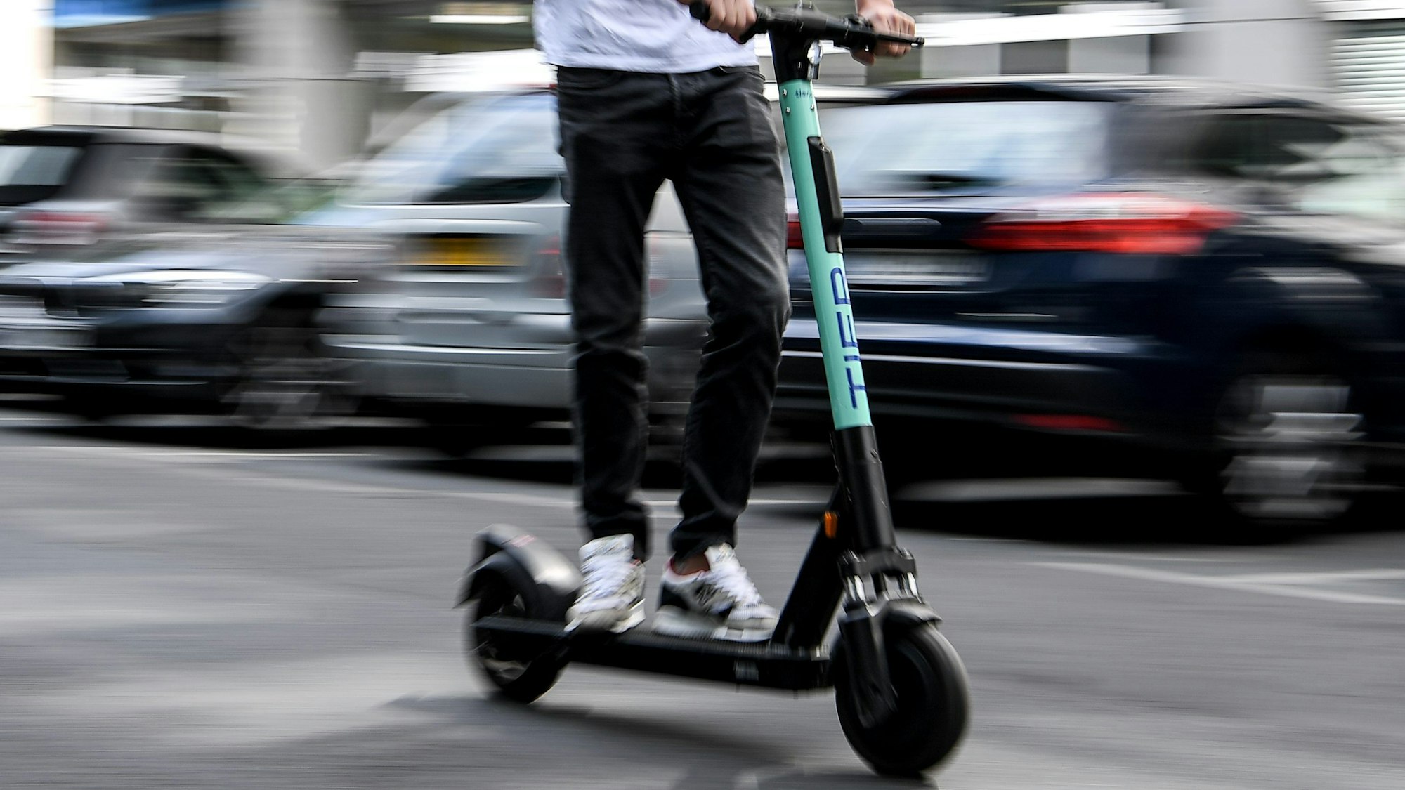 Ein Mann fährt mit einem E-Scooter auf der Straße.
