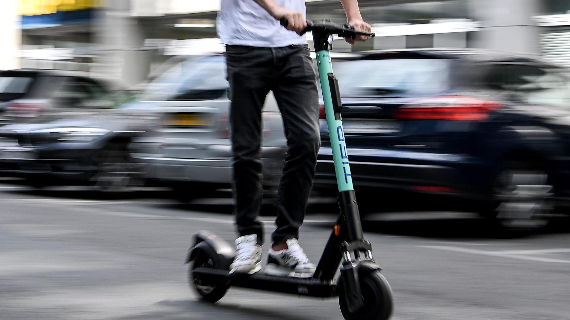 Ein Mann fährt mit einem E-Tretroller auf der Straße.