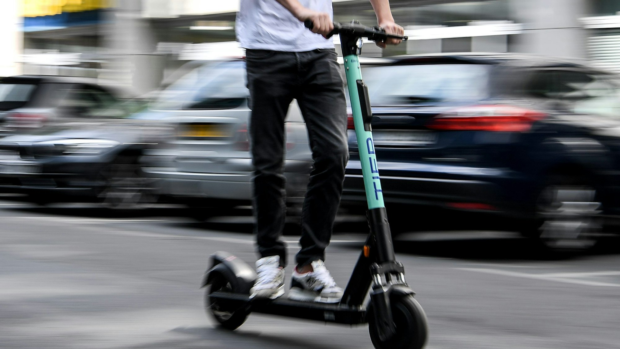 Ein Mann fährt mit einem E-Tretroller auf der Straße.