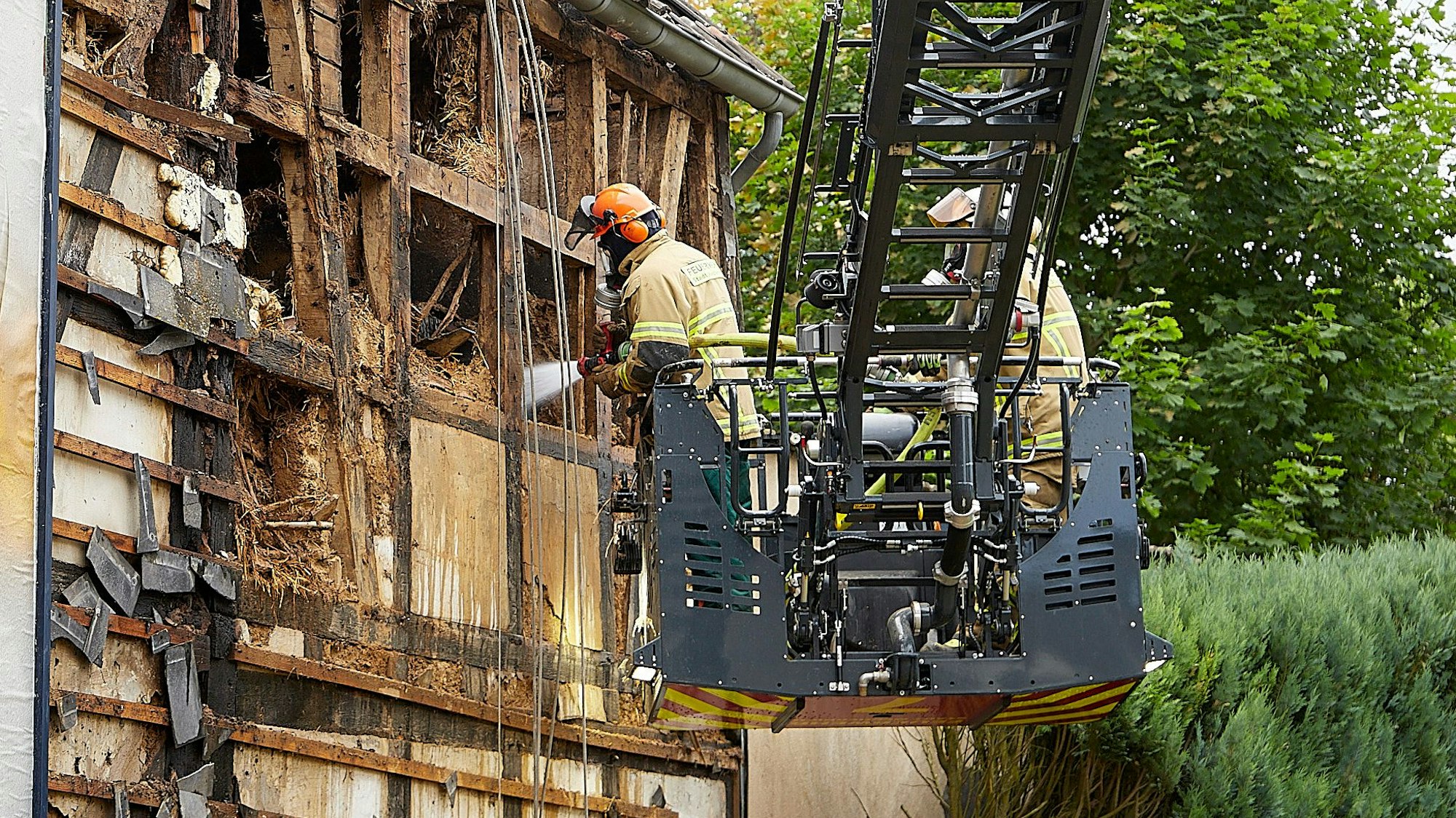 Das Bild zeigt, wie zwei Feuerwehrleute einzelne Glutnester im Fachwerk löschen.