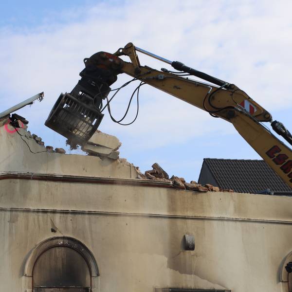 Ein Bagger reißt den Hausgiebel ein.
