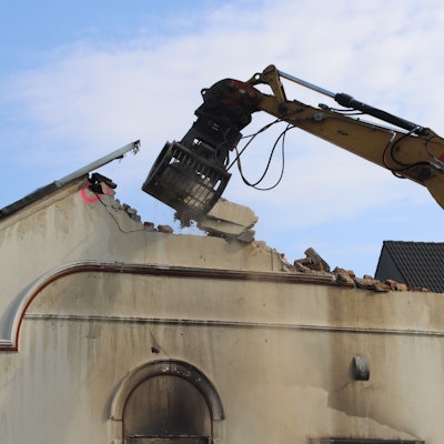 Ein Bagger reißt den Hausgiebel ein.