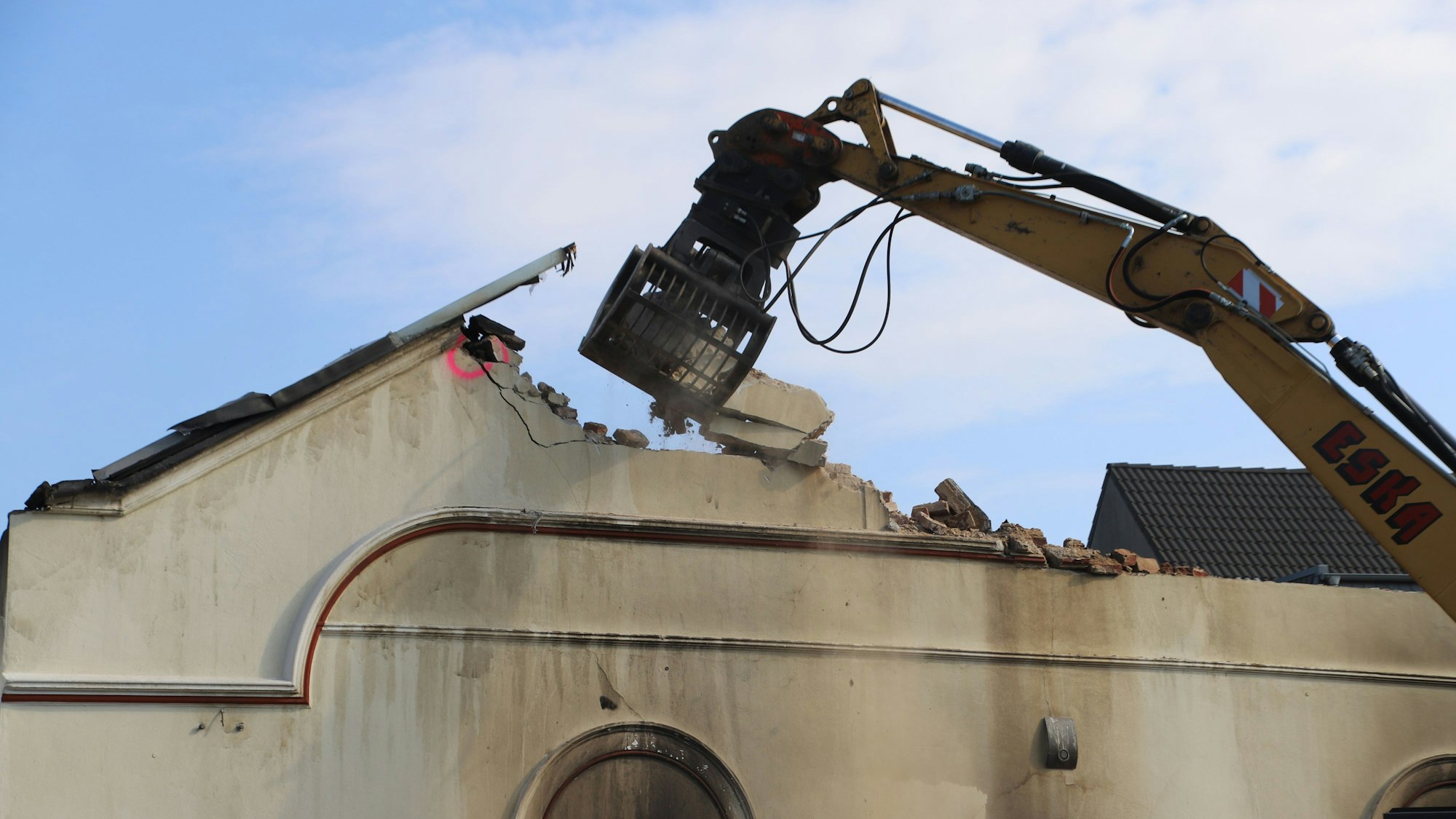 Ein Bagger reißt den Hausgiebel ein.