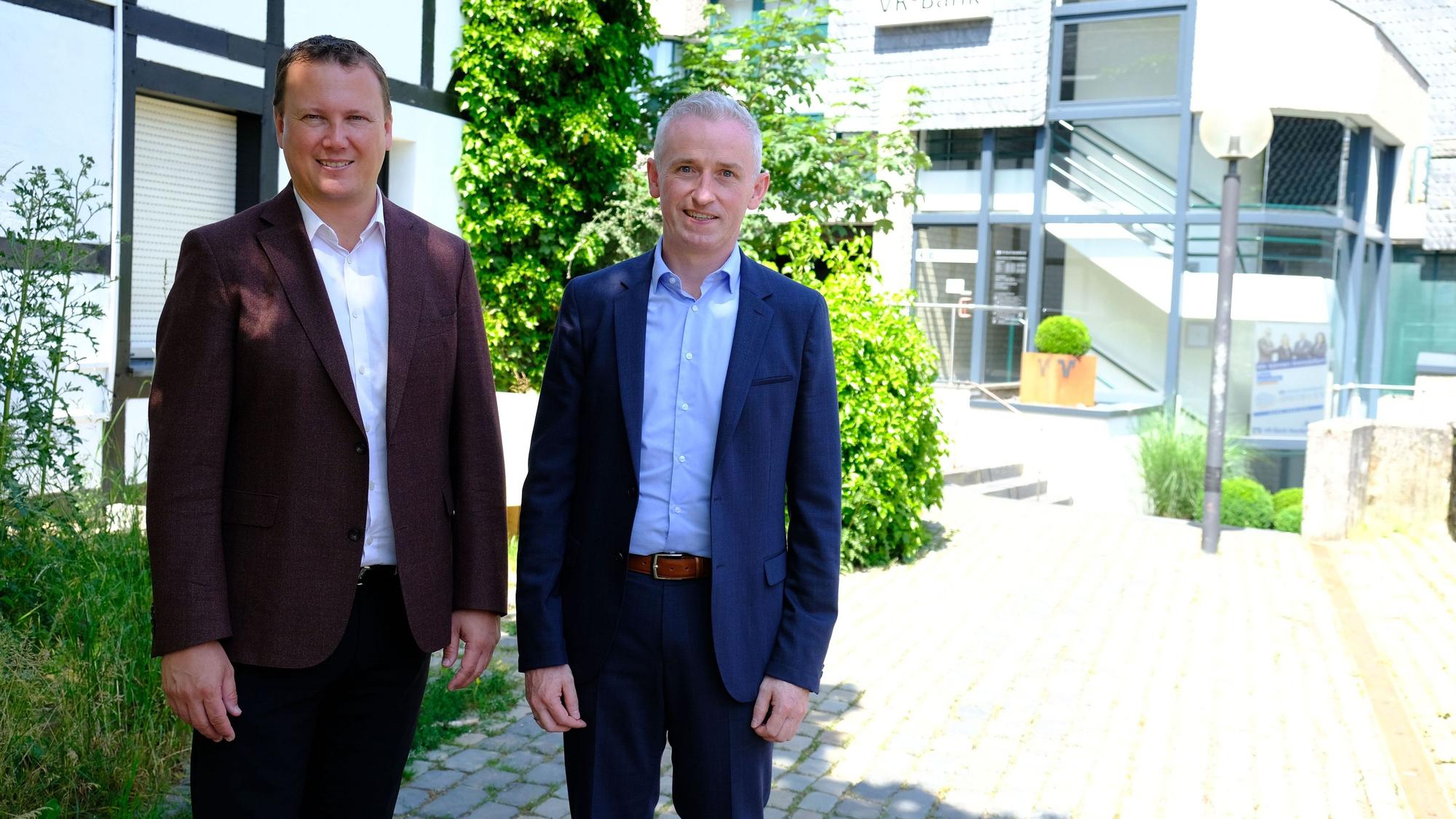 Zwei Männer im Sakko vor dem Gebäude der VR-Bank Nordeifel in Blankenheim.