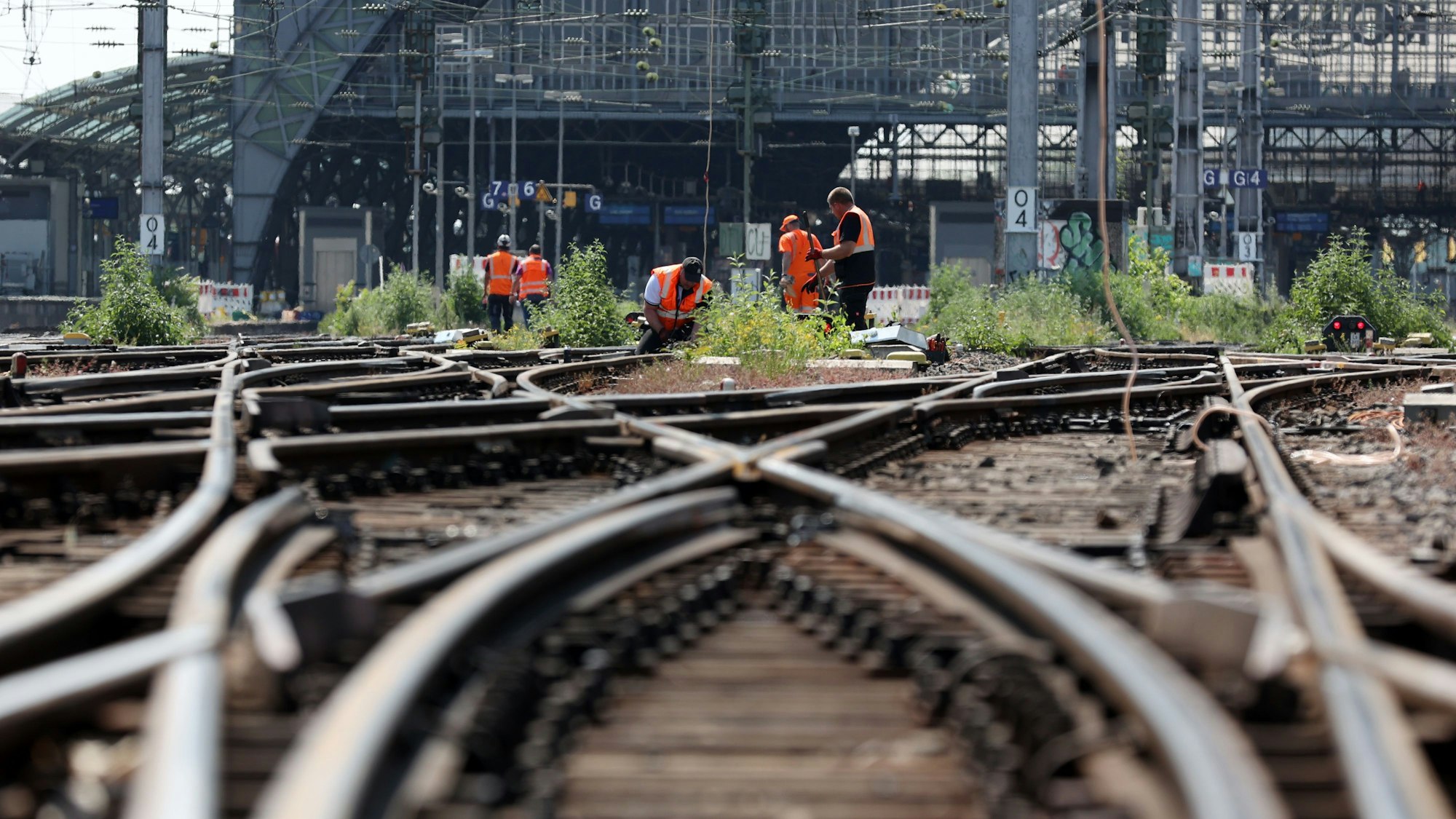 Der Kölner Hauptbahnhof wird am Sonntag komplett gesperrt. Auf dem Bild ist die Einfahrt aus Schienenperspektive zu sehen. Bauarbeiter in orangen Westen werkeln an Gleisen.
