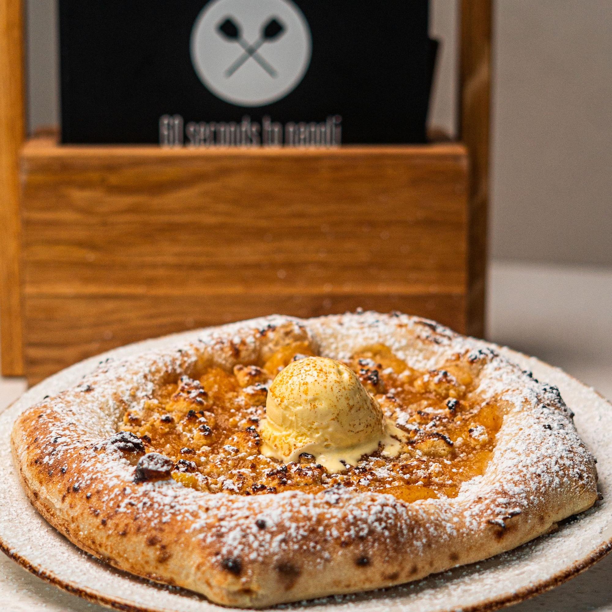 Eine Pizza mit einer Kugel Eis belegt steht auf einem Tisch.