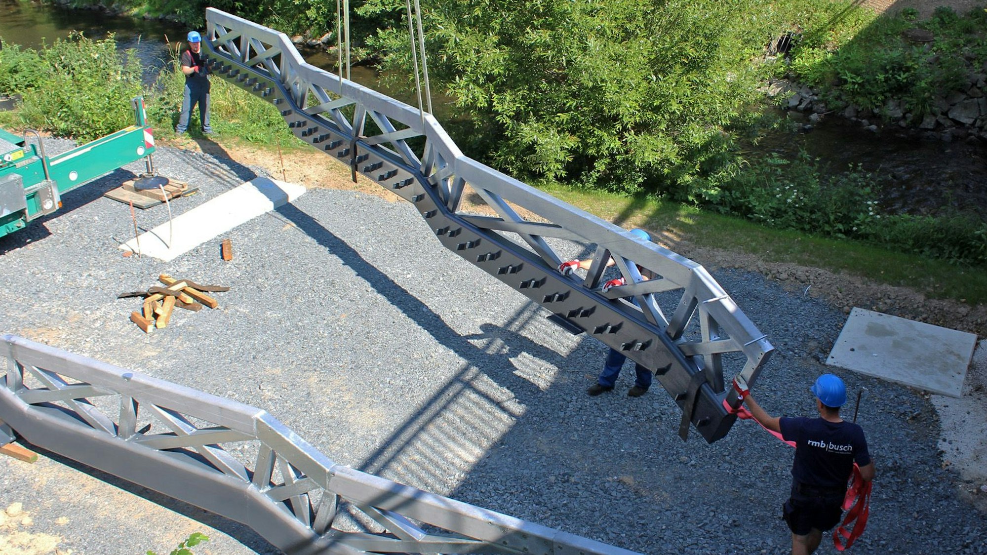 Schwere Seitenteile einer Brücke hängen an Kranseilen.