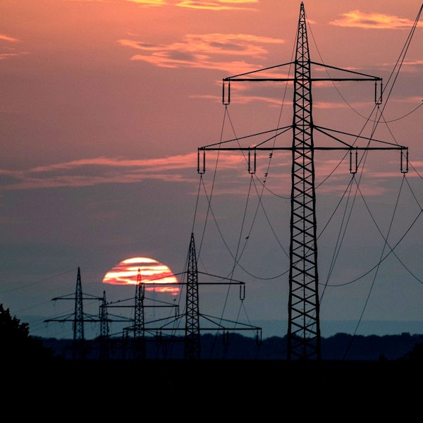 Das Bild zeigt mehrere Strommaste. Im Hintergrund geht die Sonne unter.