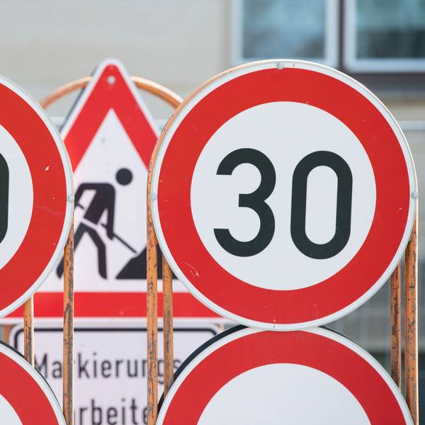 Verkehrsschilder für eine Baustelle und Tempo 30 Schilder stehen an einer Baustelle auf einem Anhänger.