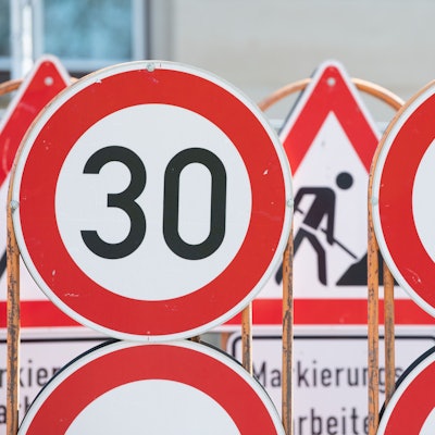 Verkehrsschilder für eine Baustelle und Tempo 30 Schilder stehen an einer Baustelle auf einem Anhänger.