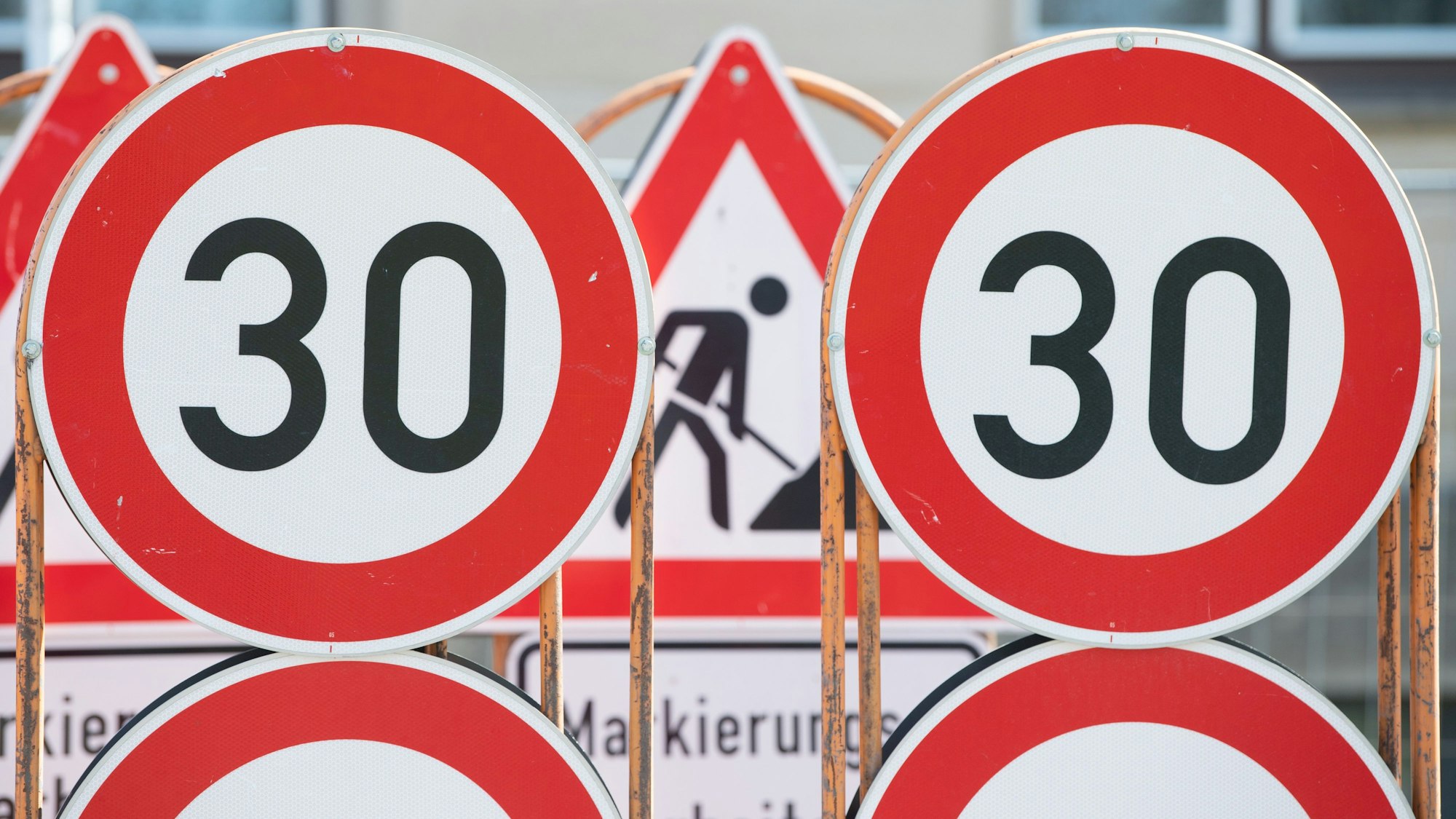 Verkehrsschilder für eine Baustelle und Tempo 30 Schilder stehen an einer Baustelle auf einem Anhänger.
