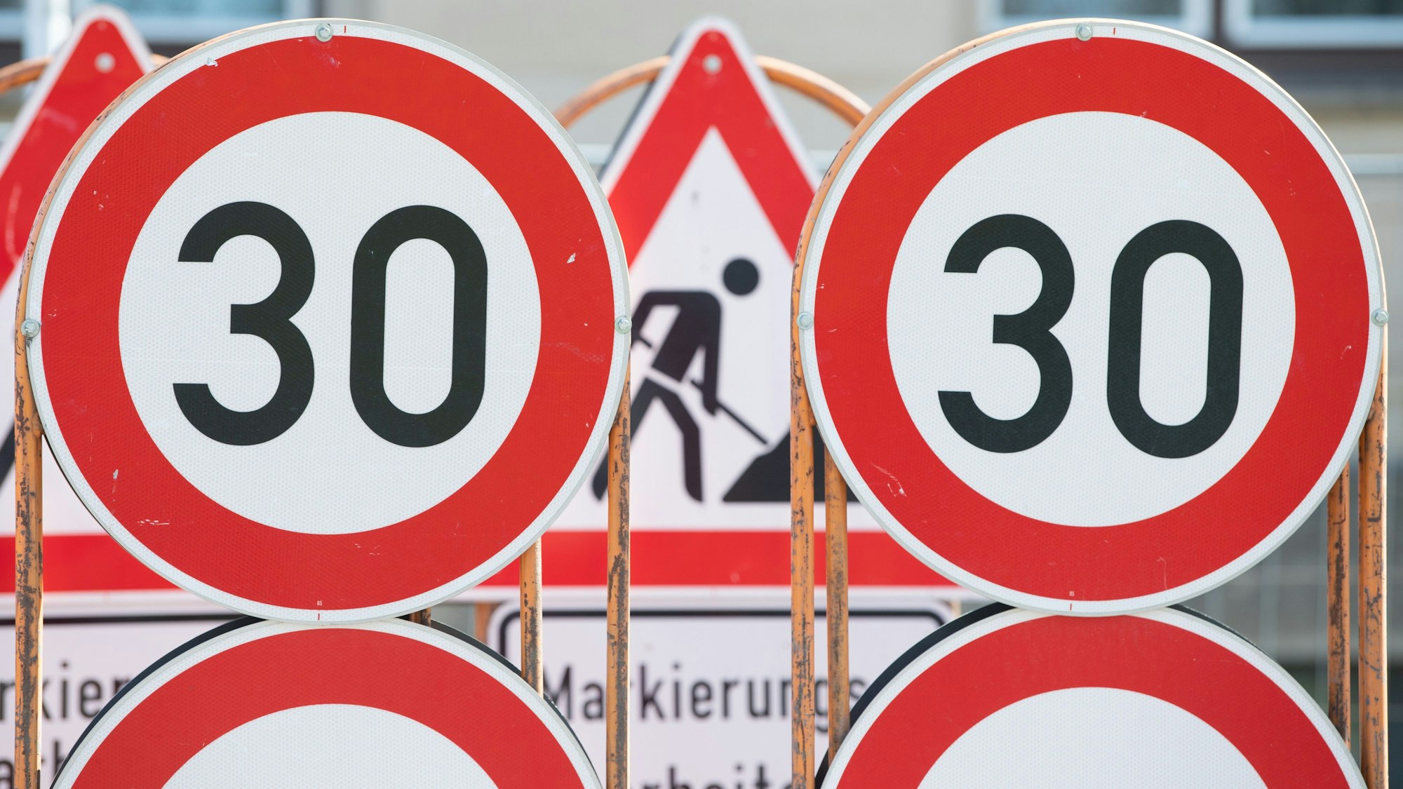 Verkehrsschilder für eine Baustelle und Tempo 30 Schilder stehen an einer Baustelle auf einem Anhänger.