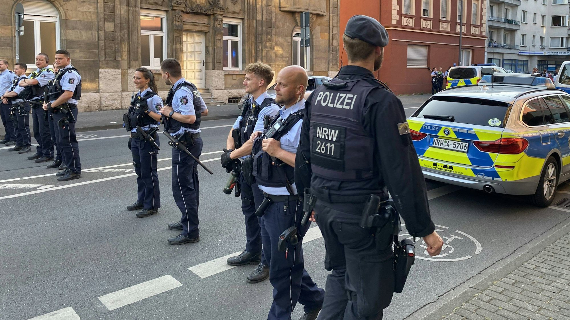 Castrop-Rauxel: Polizisten stehen am Rande einer Massenschlägerei. Diese ist aber nicht zu sehen. Die Beamten stehen mit Schutzweste in einer Reihe, hinter ihnen parkt ein Polizeiauto.