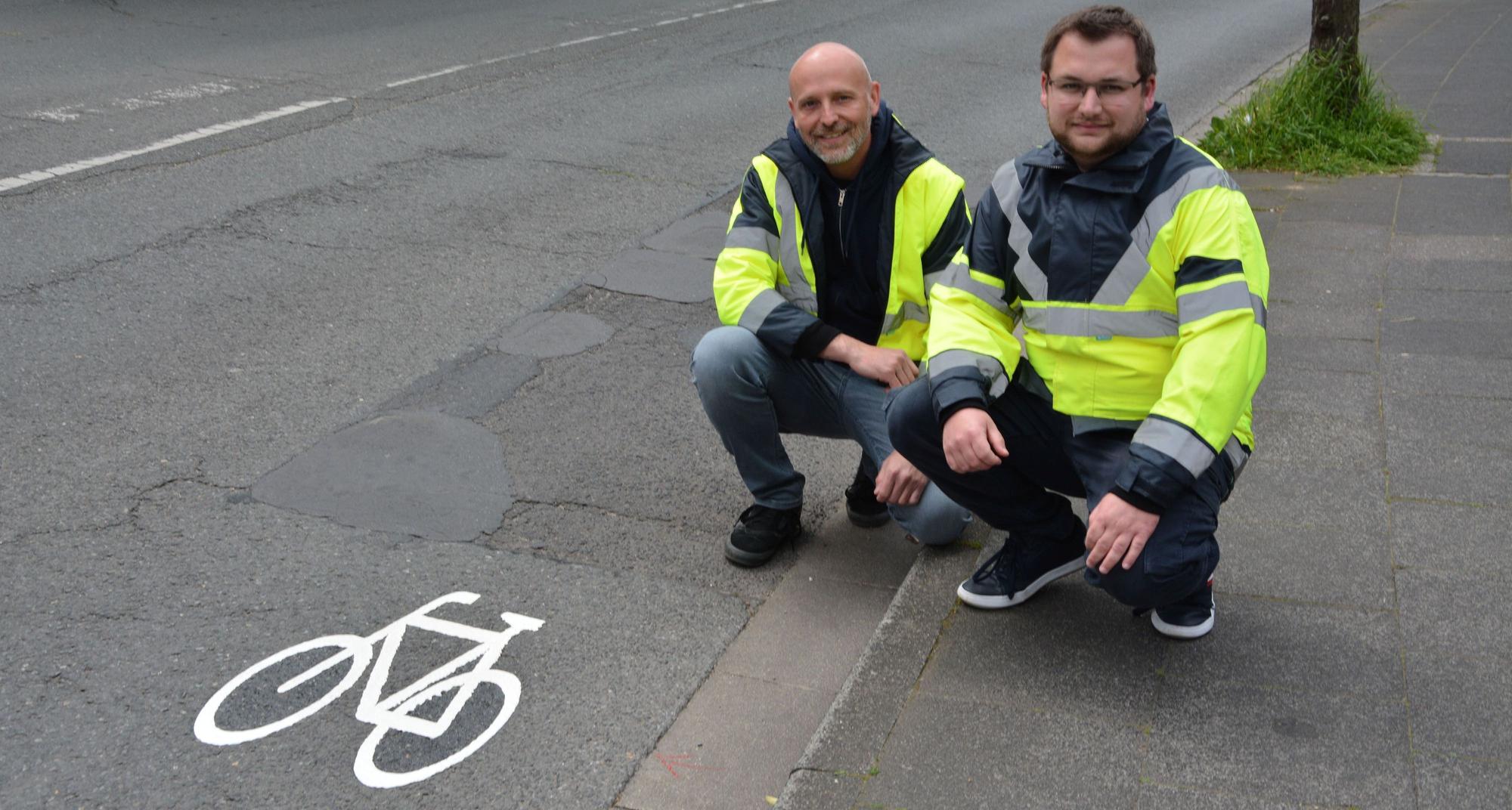 Tobias Siefen von der Unteren Straßenverkehrsbehörde und Tiefbauamtsleiter Martin Jagusch (v.r.) an einem der neuen Piktogramme.