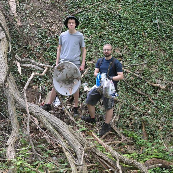 Die Jungs stehen im Wald und halten Müll in ihren Händen.