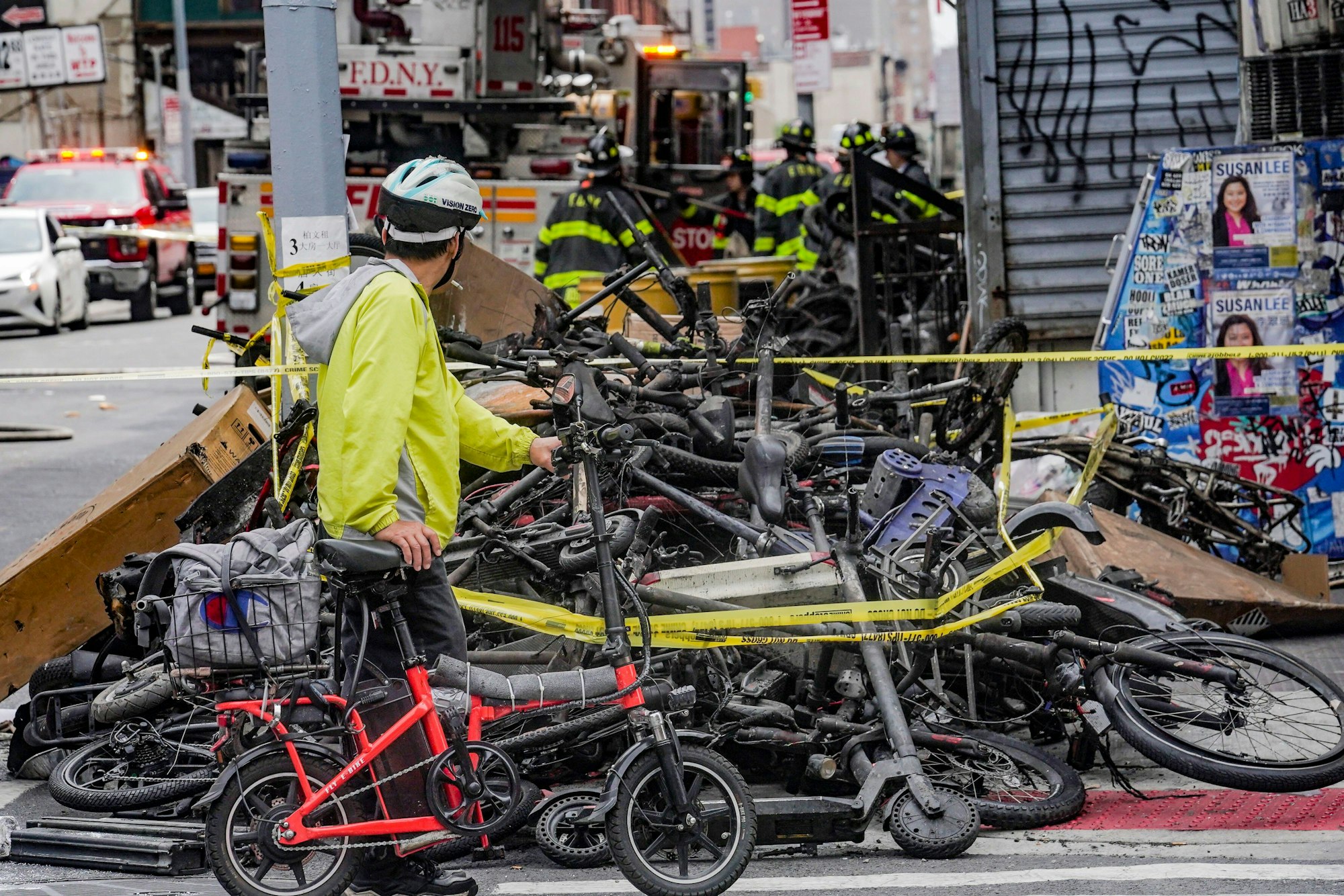USA, New York: Ein Radfahrer hält an, um einen Stapel von E-Bikes nach einem Brand in Chinatown zu betrachten, der nach Angaben der Behörden in einem E-Bike-Laden ausgebrochen ist und sich auf Wohnungen in den oberen Stockwerken ausgebreitet hat.