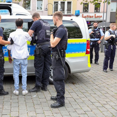 Polizisten bringen einen gefesselten, mutmaßlichen Taschendieb zu einem Streifenwagen.