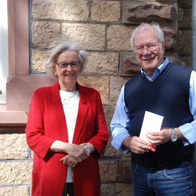 Das Bild zeigt einen Mann und eine Frau vor einer Bruchsteinwand.