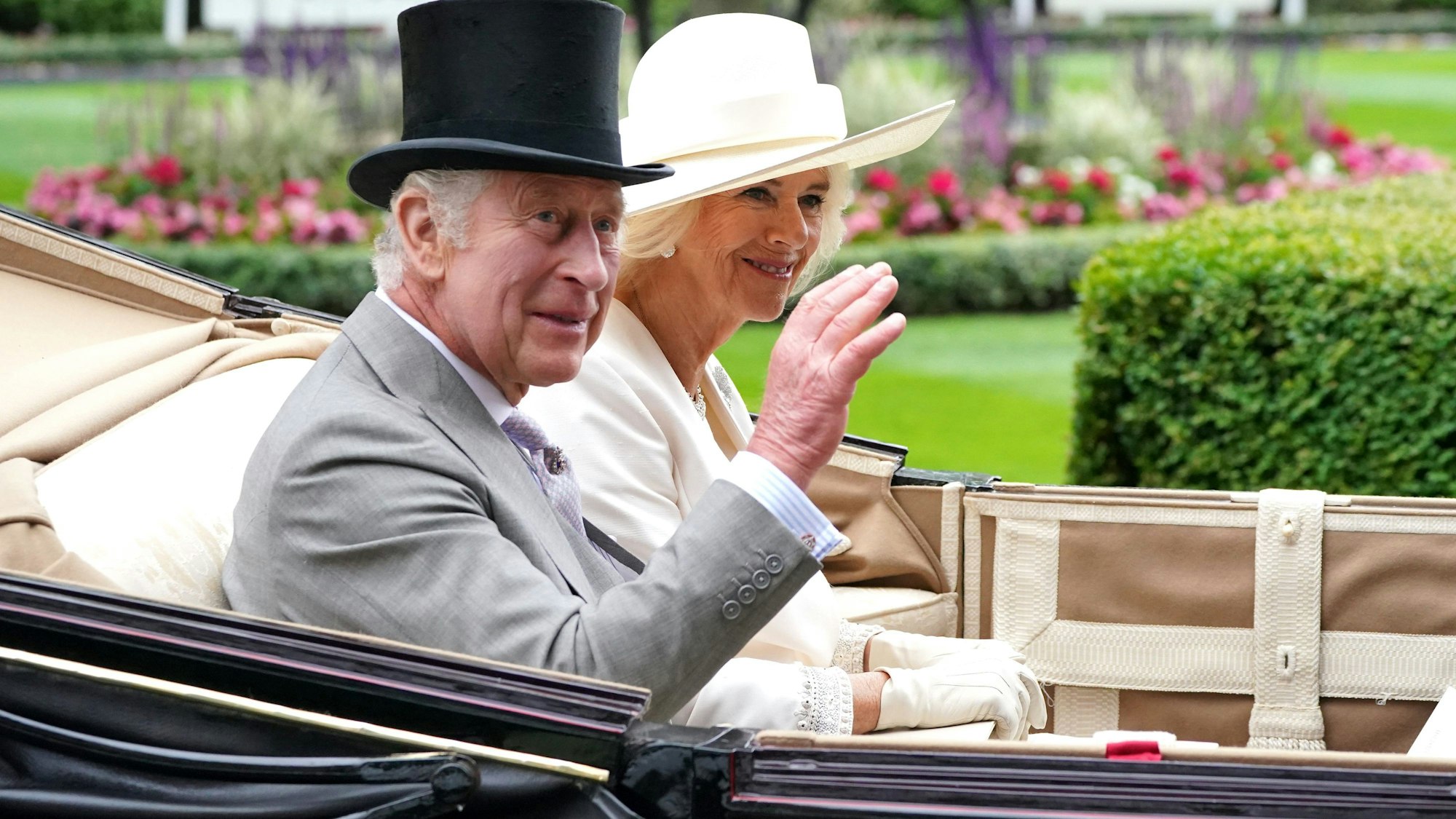 König Charles III. und Königin Camilla von Großbritannien winken der Menge am ersten Tag der Royal-Ascot-Rennwoche auf der Pferderennbahn von Ascot.