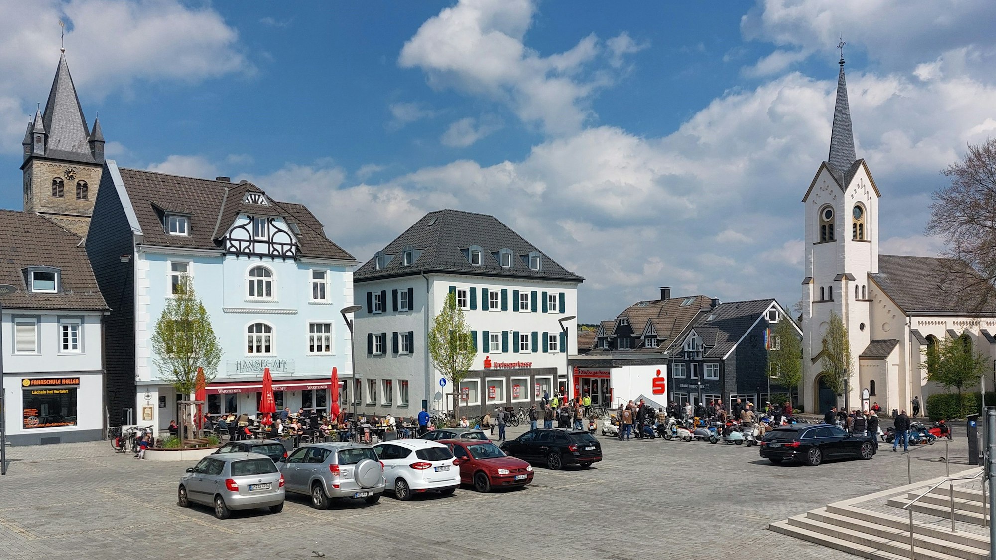Blick auf den Platz. Einige Autos parken in der Mitte.