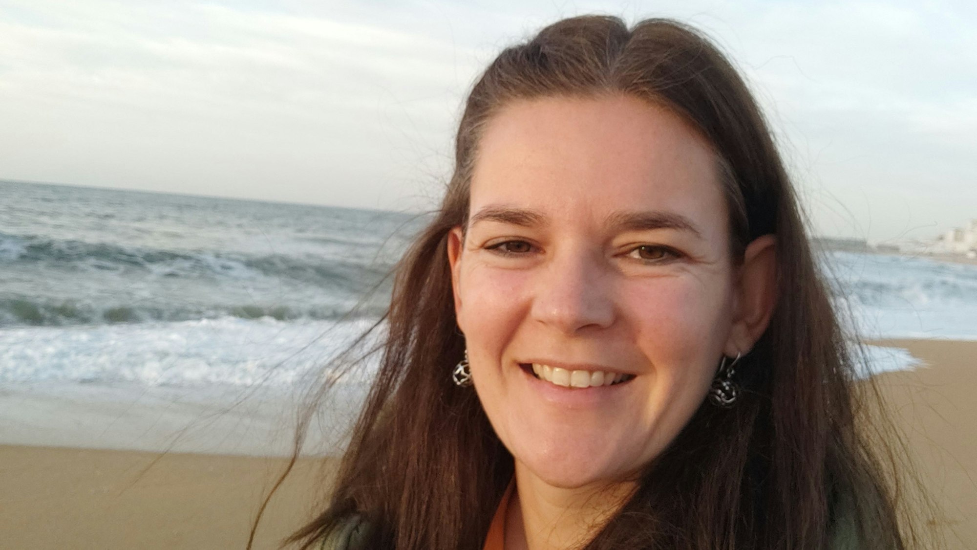 Eine Frau steht am Strand vor dem Meer.