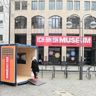 Das Bild zeigt das frühere Modehaus Sauer und einen Container davor.