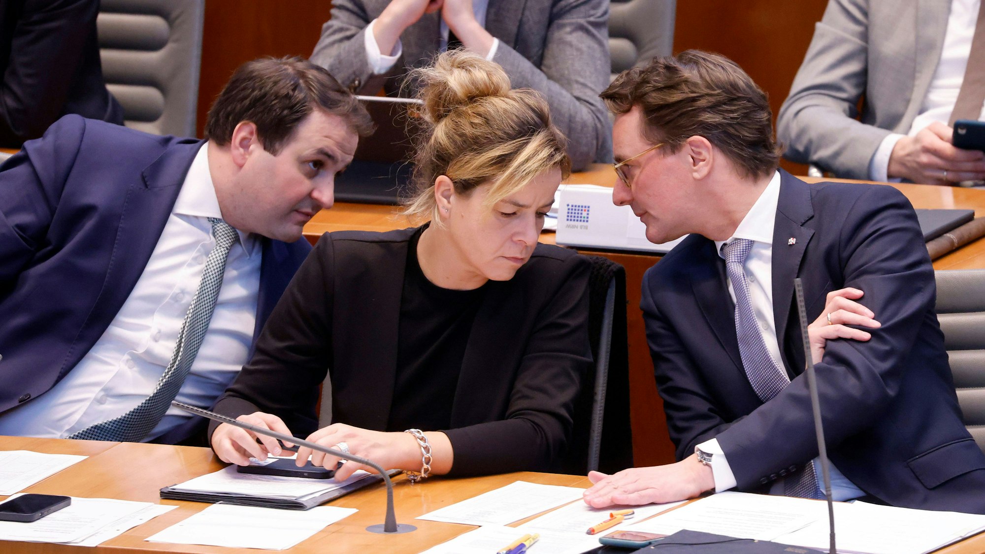 Nathanael Liminski, Leiter der Staatskanzlei NRW, Mona Neubaur, Grünen, Ministerin für Wirtschaft, und Hendrik Wüst, Ministerpräsident des Landes Nordrhein-Westfalen, sind im NRW-Landtag ins Gespräch vertieft.