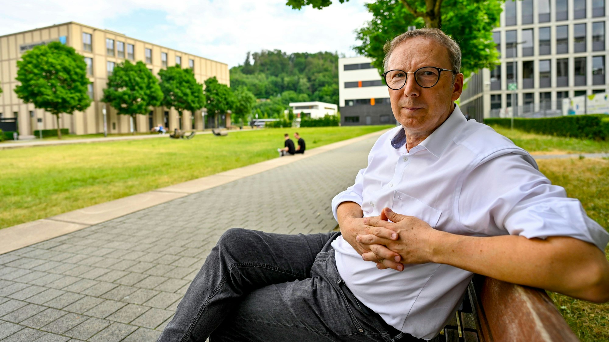 Ein Mann sitzt im Grünen auf einer Bank.