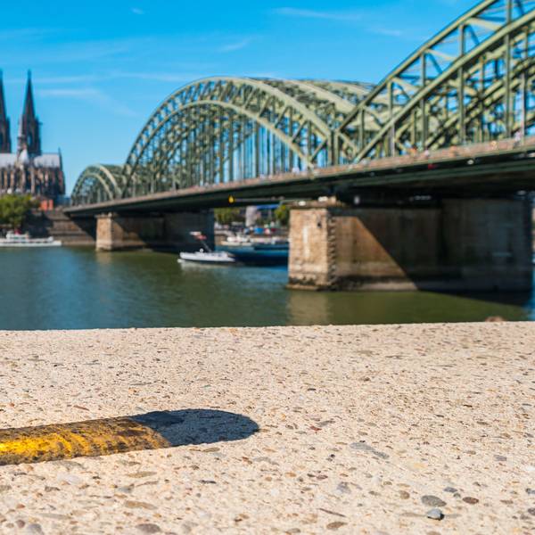 Kölschglas am Rhein. Im Hintergrund die Hohenzollernbrücke und der Dom.