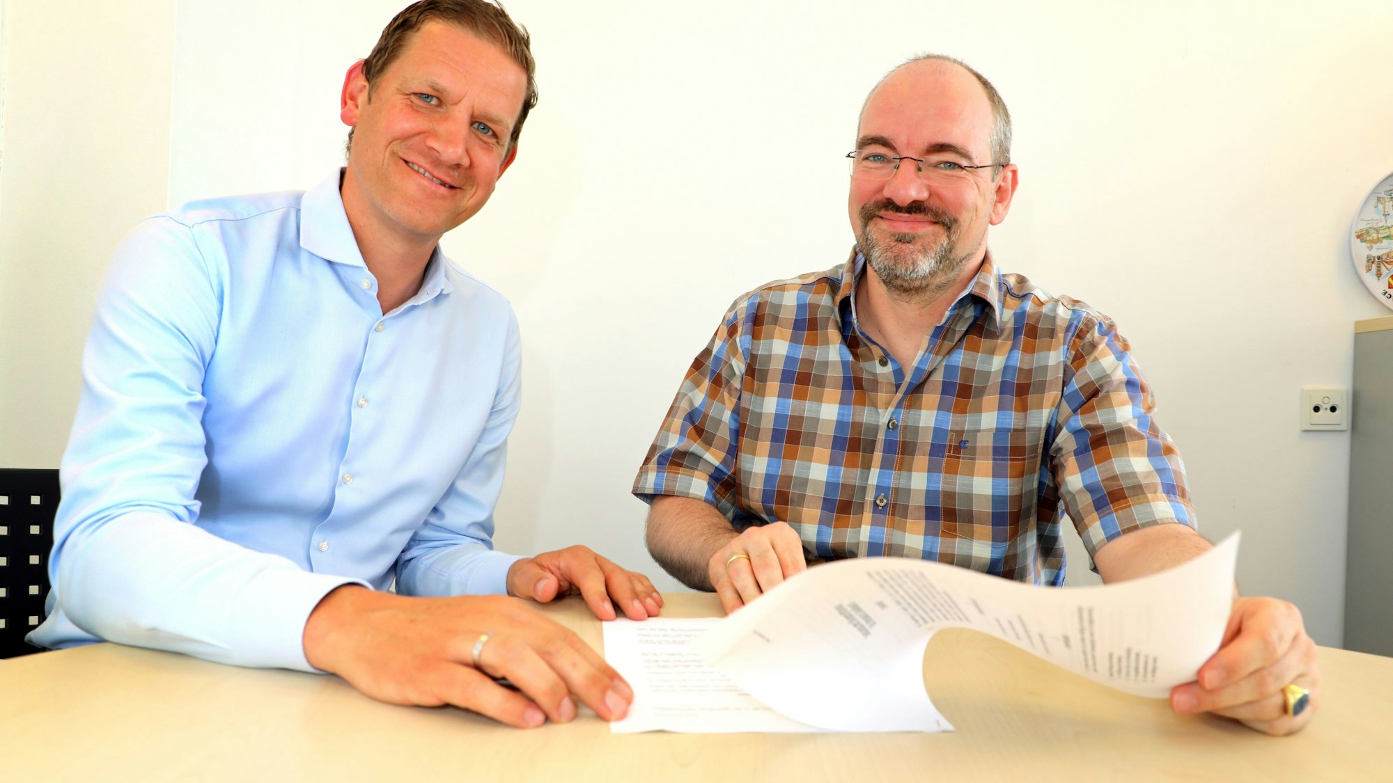 Der Vorstandsvorsitzende der Bergisch Gladbacher Bürgerstiftung, Alexander Pfister, und sein Vorstandskollege Raphael Franken sitzen an einem Tisch und schauen in die Satzung der Stiftung.