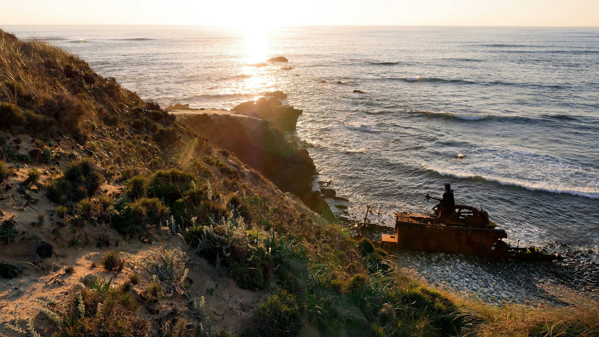 Das Wrack des Schleppers Klemens rostet im Sonnenuntergang vor sich hin.