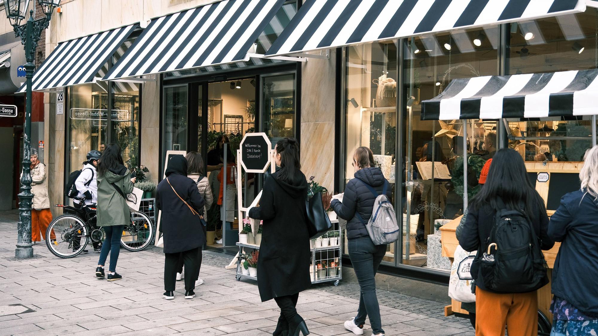 Kundinnen und Kunden stehen vor einer Filiale des Einrichtungshauses „Dille & Kamille“ in der Düsseldorfer Altstadt.