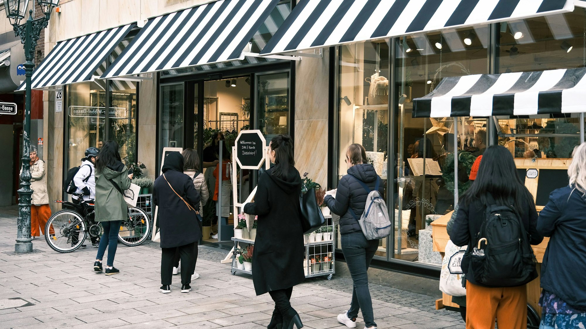 Kundinnen und Kunden stehen vor einer Filiale des Einrichtungshauses „Dille & Kamille“ in der Düsseldorfer Altstadt.