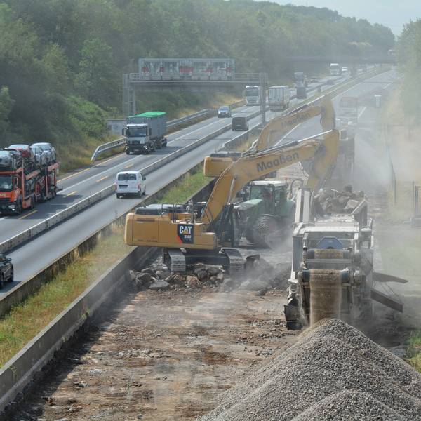 Baustellenfahrzeuge versperren die Fahrt auf der einen Richtung, der Verkehr weicht auf die andere Seite aus.