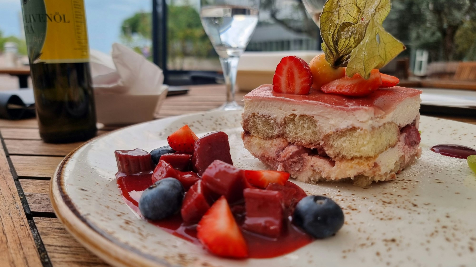 Ein sehr schön mit Beeren angerichtetes Erdbeer-Tiramisu auf einem Teller.