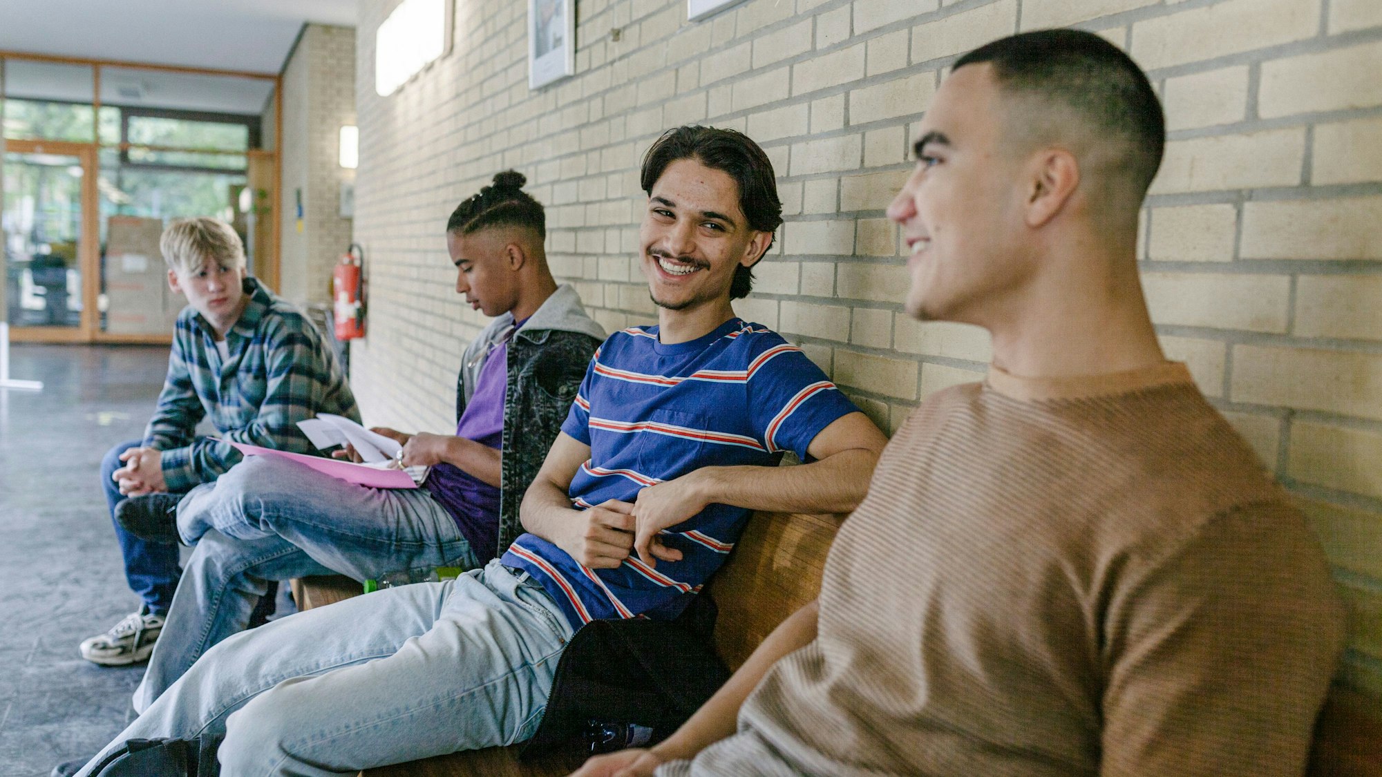 Jungs sitzen in der Schule auf Bänken und lachen.