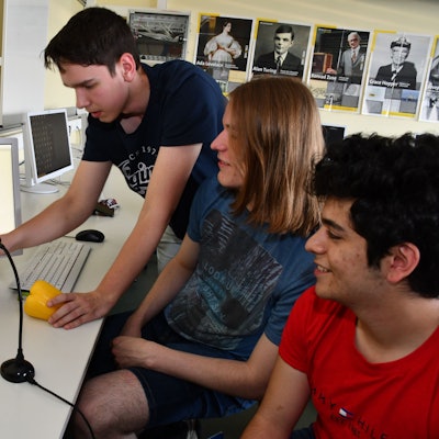 Das Foto zeigt drei Schüler und Obst vor einem Computer.