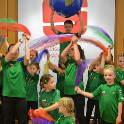 Kinder schwenken Tücher im S-Forum der Kreissparkasse.