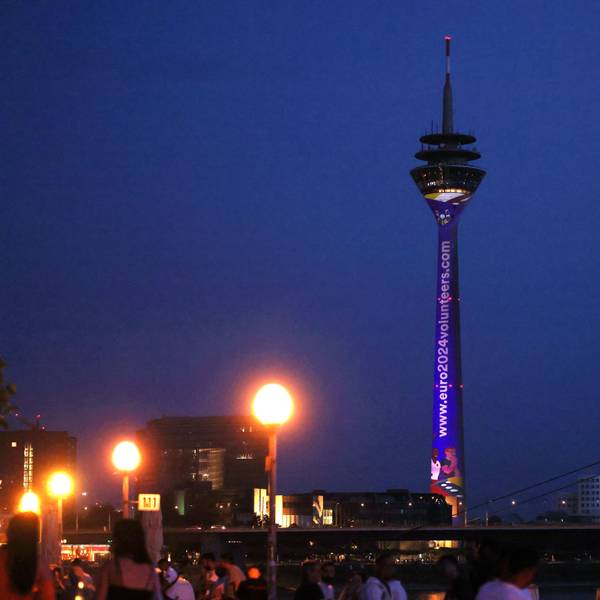 Der Düsseldorfer Fernsehturm und das Rheinufer in der Abenddämmerung.
